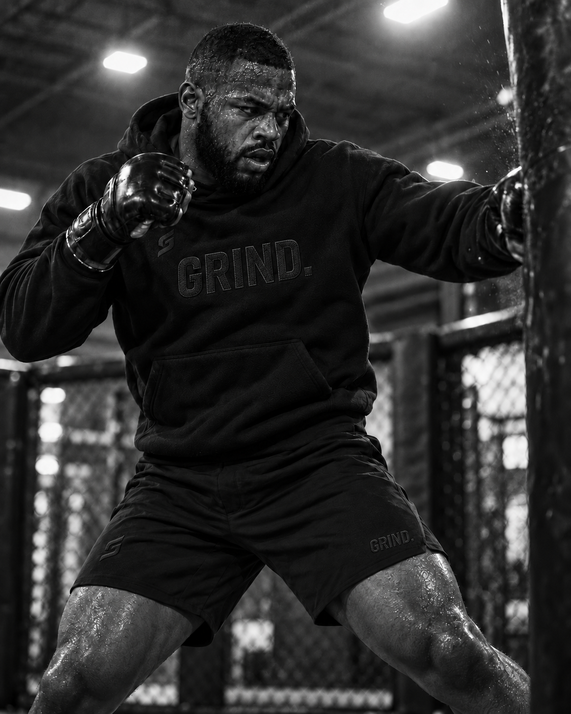 Black male athlete wearing the GRIND. heavyweight hoodie while striking a heavy bag